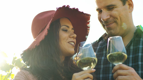 Portrait of smiling friends toasting wineglasses against white background