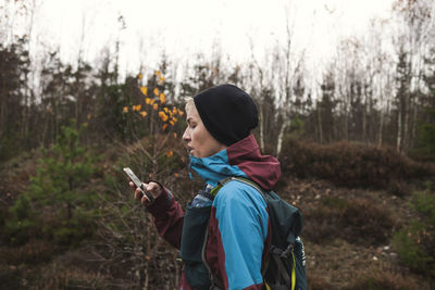 Side view of man looking at camera in forest