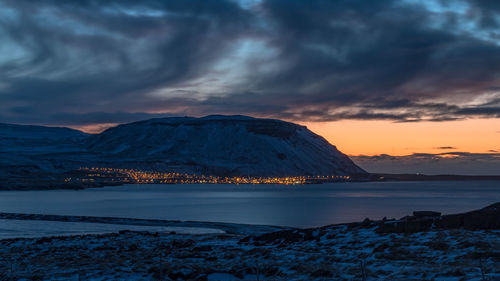 Panoramic view of small city lights at the base of a mountain next to the ocean