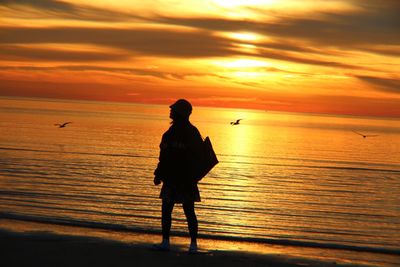 Silhouette man standing on beach during sunset