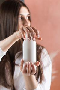 Beauty portrait. a beautiful brunette girl holds in her hands a white template tube 