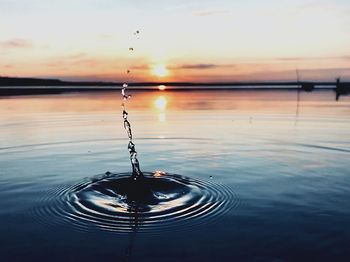 Water splashing in lake against sky during sunset