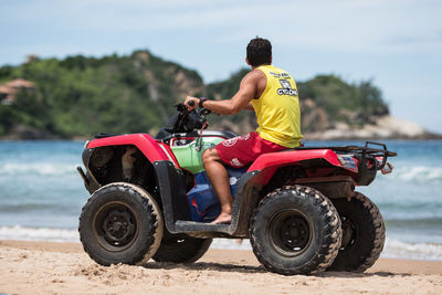 Rear view of man riding motorcycle on beach