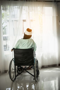 Rear view of woman with bandaged head sitting on wheelchair hospital