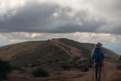 Rear view of man standing on land against sky