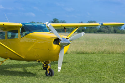 Yellow airplane on airport runway against sky