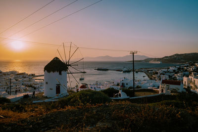 Buildings by sea against clear sky during sunset