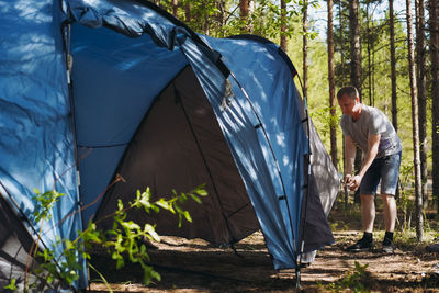 Caucasian man wearing a hat putting up a tent. family camping concept