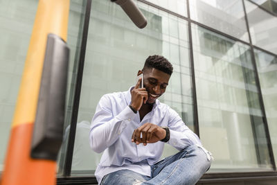 Young man checking time and talking on smart phone