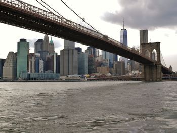 Bridge over river in city against sky