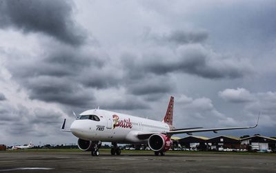 Airplane on airport runway against sky