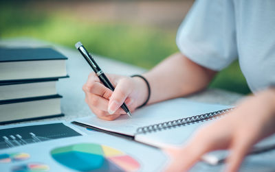 Midsection of woman writing in book