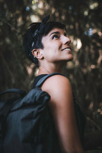 Portrait of a smiling young woman looking away in the forest