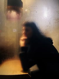 Rear view of woman looking through window