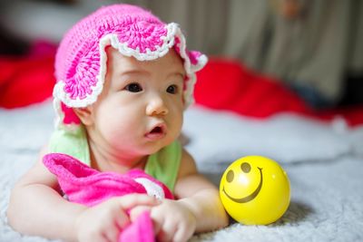 Cute baby girl looking away while lying on bed