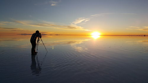Man standing on beach against sky during sunset