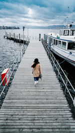 Rear view of woman walking on pier over sea