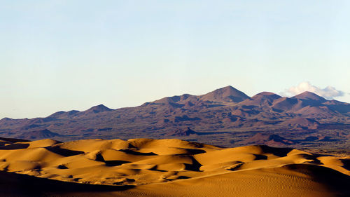 Scenic view of desert against clear sky on sunny day