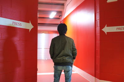 Rear view of woman standing against wall