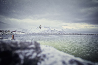 Scenic view of sea by snowcapped mountain against sky