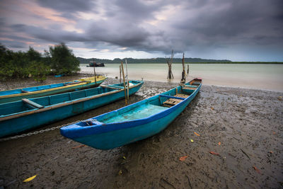 Boats moored on shore against sky