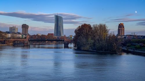 Bridge over river by buildings against sky in city