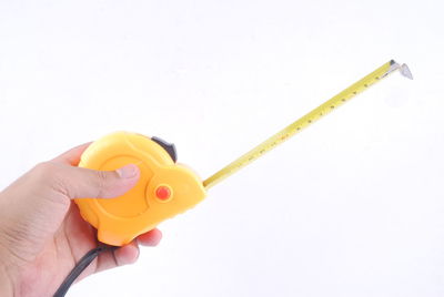 Close-up of hand holding yellow paper against white background