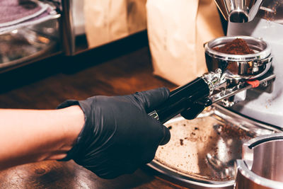 Cropped hand of barista holding portafilter coffee in cafe