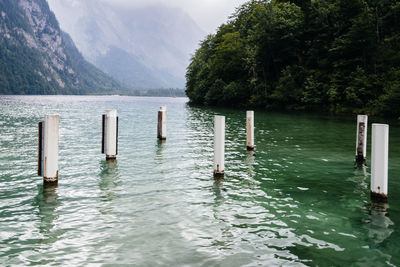 Wooden posts in lake against mountains