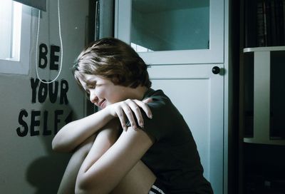 Boy looking away while sitting on door