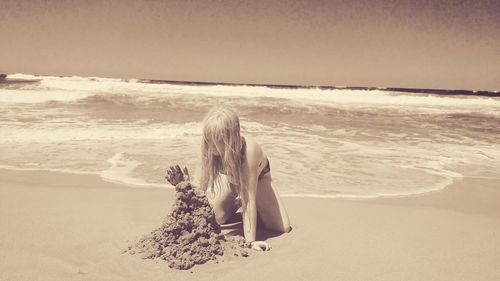 Woman on beach by sea against sky
