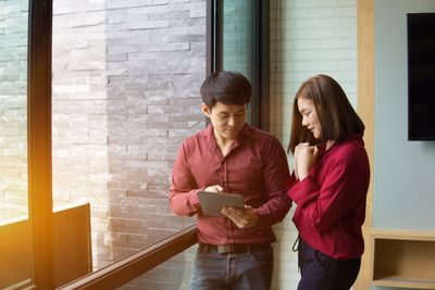 Business colleagues using digital tablet while standing in office