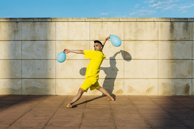 Full length of man holding ball against wall