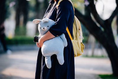 Midsection of woman holing toy while standing on footpath