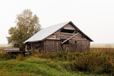 Abandoned house on field against clear sky