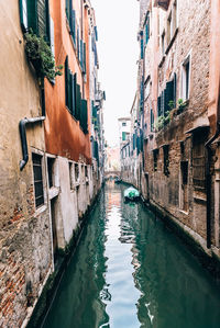 Canal amidst buildings against clear sky