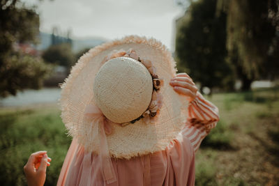 Portrait of woman holding hat standing against plants during winter