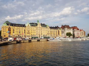 River by buildings in city against sky