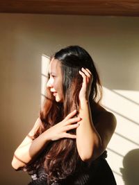 Thoughtful young woman standing against wall