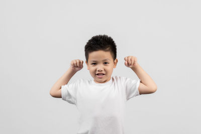 Portrait of smiling boy standing against white background