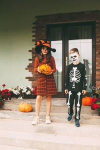 Brother and sister celebrate halloween on the street near the house in costumes and make-up 