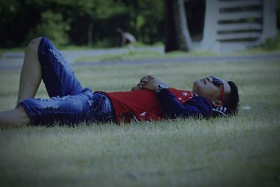 Rear view of boy lying on grass in field