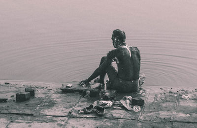 Rear view of man bathing at riverbank