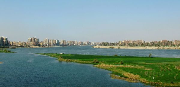 Scenic view of river by city against clear sky