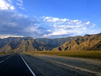 Road leading towards mountains against sky