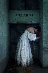 Rear view of woman standing against wall