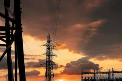 Low angle view of electricity pylon against sky during sunset