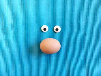 Directly above shot of googly eyes and egg on fabric during easter