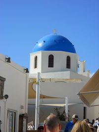 People in front of building against clear blue sky