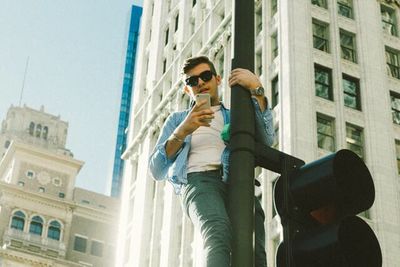Low angle view of woman holding sunglasses in city